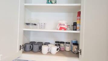 A kitchen cabinet with various kitchenware and containers.