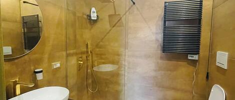 Un baño moderno con un espejo grande, un lavamanos, un inodoro y una ducha.