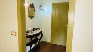 A hallway with a wooden floor, a dining table with a white and blue patterned tablecloth, and a green door at the end. - La casa di Erica (Naples)