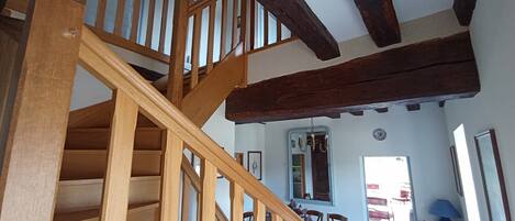 A wooden staircase with a ceiling fan, a dining area with a table and chairs, and a chandelier.