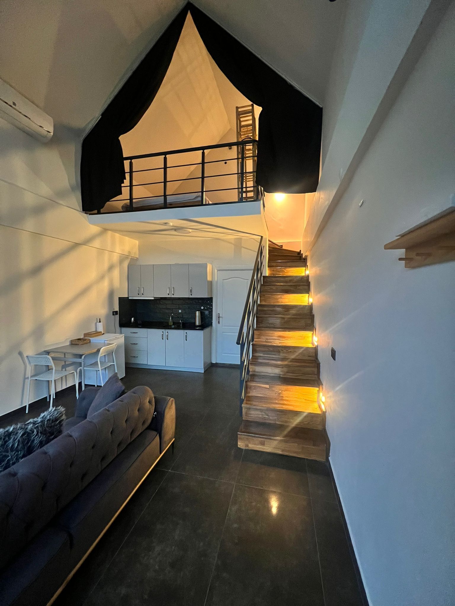A modern interior with a loft bedroom, a dining area, and a kitchen.