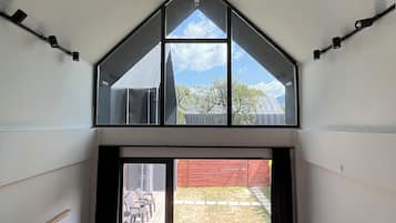 Una habitación estilo loft moderna con un tragaluz grande, un sofá con cojines y vistas al patio trasero.