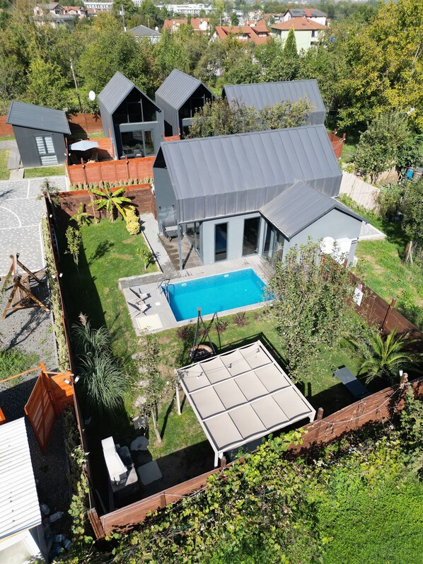 Une maison moderne dotée d’une piscine, d’un patio couvert et d’un jardin clôturé.