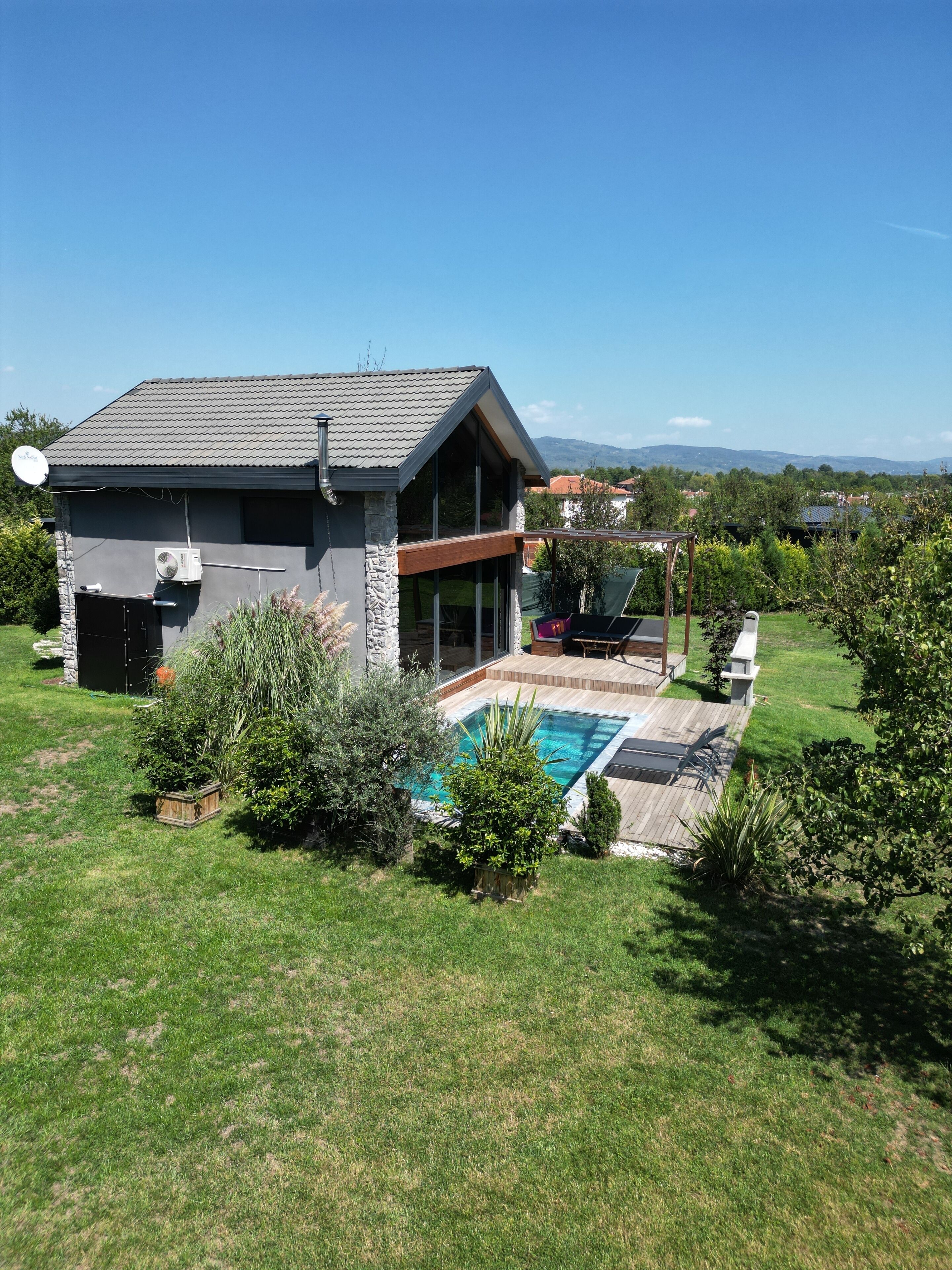 Una casa moderna amb piscina, façana de pedra i grans finestres.