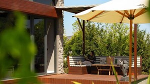 A modern outdoor pool area with a stone wall, a wooden deck, and a seating area with a large umbrella. - Monk Livingspace (Kartepe)