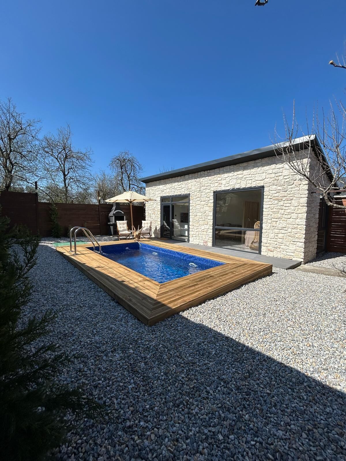 A modern house with a swimming pool, stone exterior, and a patio area.