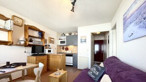 A compact living space with a kitchenette, a dining area, and a sofa. - (7.B17) Appartement skis aux pieds Les Menuires (Les Menuires)