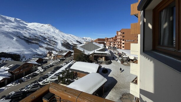 A snow-covered mountain town with buildings and parked cars. - (7.B17) Appartement skis aux pieds Les Menuires (Les Menuires)