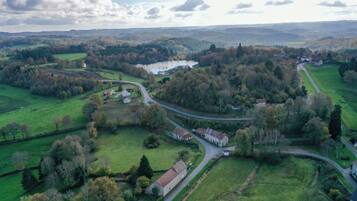 Une vue aérienne d’une zone rurale, avec une route sinueuse, des champs verdoyants et des bâtiments dispersés.