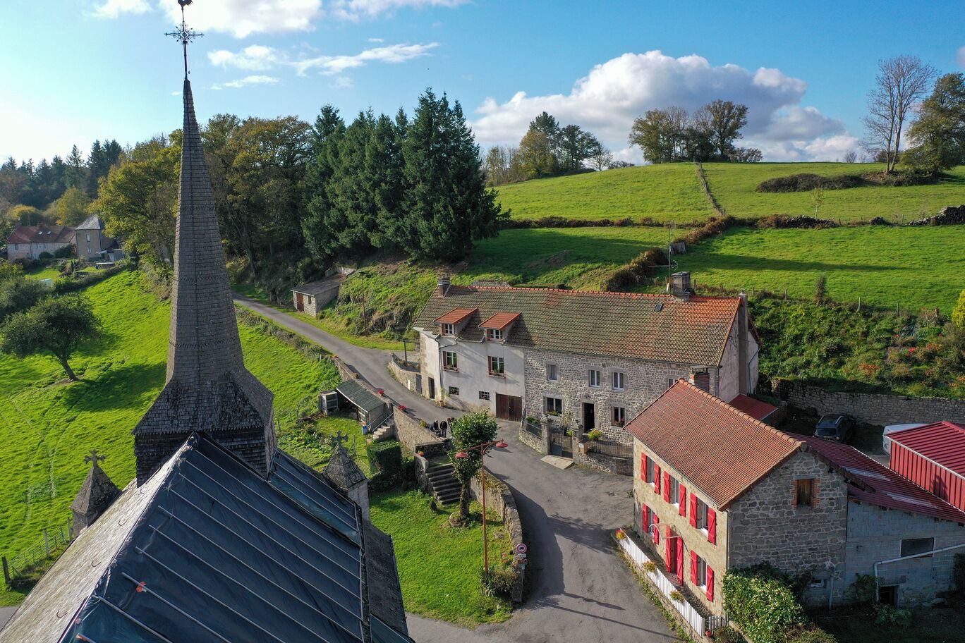 A rural village with a prominent church steeple, stone buildings, and a green landscape.