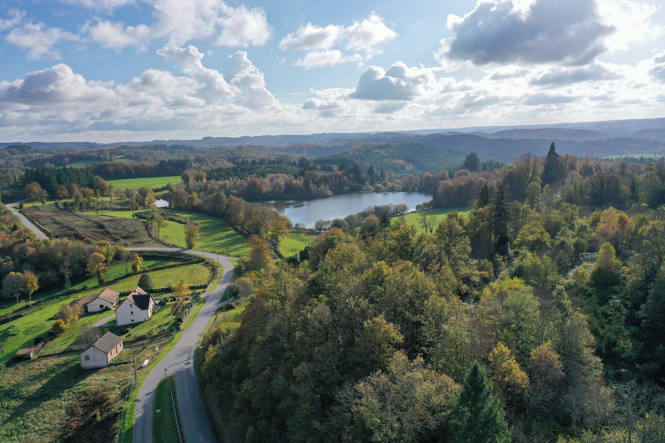 A rural landscape with a lake, rolling hills, and a winding road.