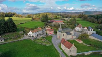 A rural village with stone buildings, a church, and green fields.
