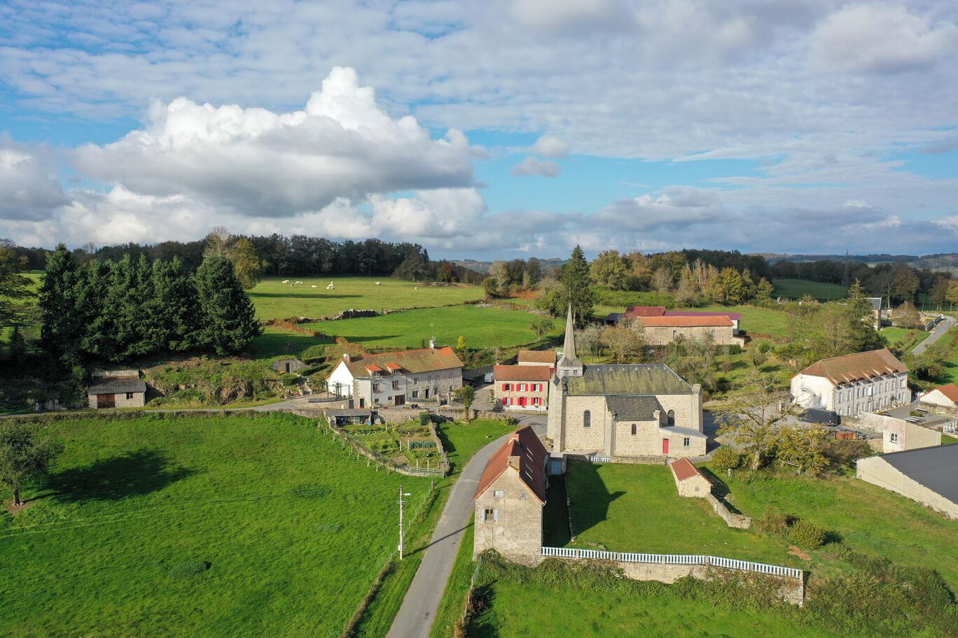 A rural village with a church, stone buildings, and green fields.