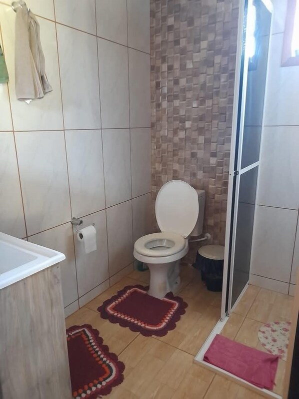 Een badkamer met een toilet, een douche en een wastafel.
