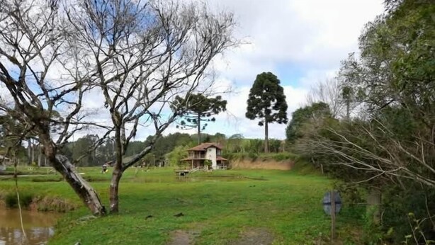 A rural landscape with a house, a pond, and a path. - Chalé sol nascente  (Campo Alegre)