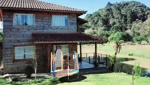 Una casa de madera con techo de tejas, un porche cubierto y un columpio en el jardín.