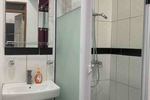 Chuveiro, toalhas de banho, sabonete, papel higiênico