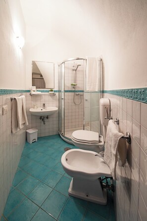 Ein kleines Badezimmer mit einer Duschkabine, einem Waschbecken und zwei Toiletten.