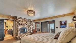 Un dormitorio con chimenea de piedra, una cama grande y vistas al exterior.