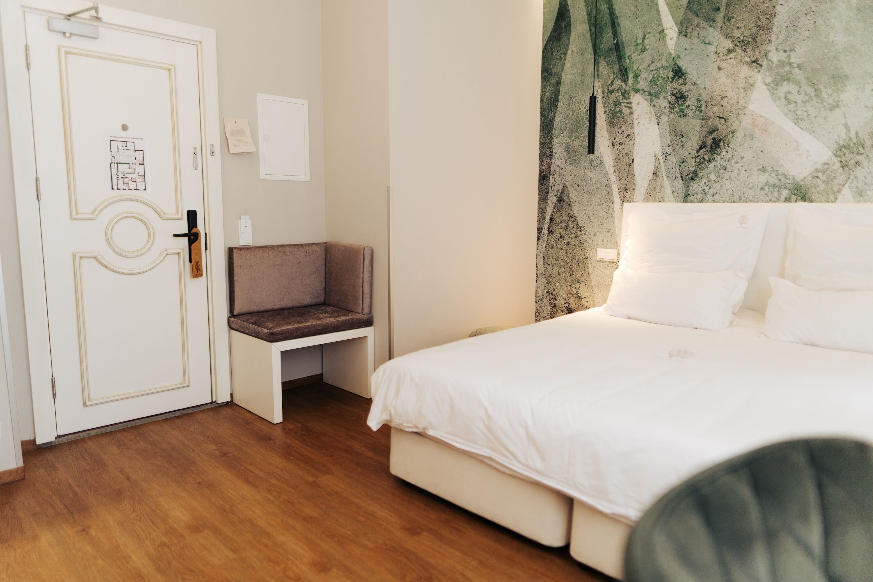 A bedroom with a bed, a desk, and a door.