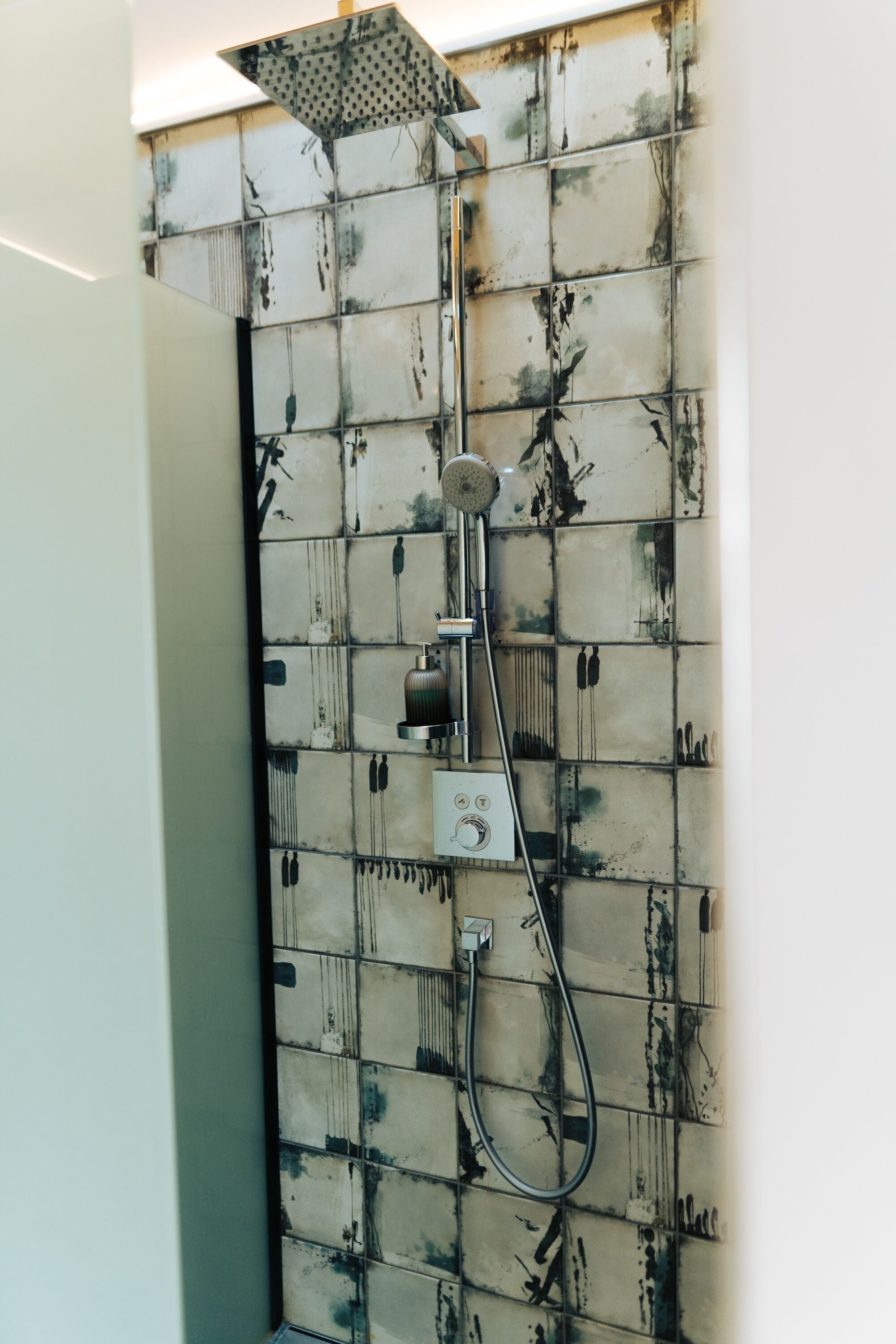 A shower with a unique tiled wall design.