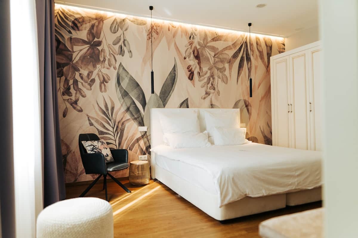 A bedroom with a large bed, a chair, and a wardrobe.