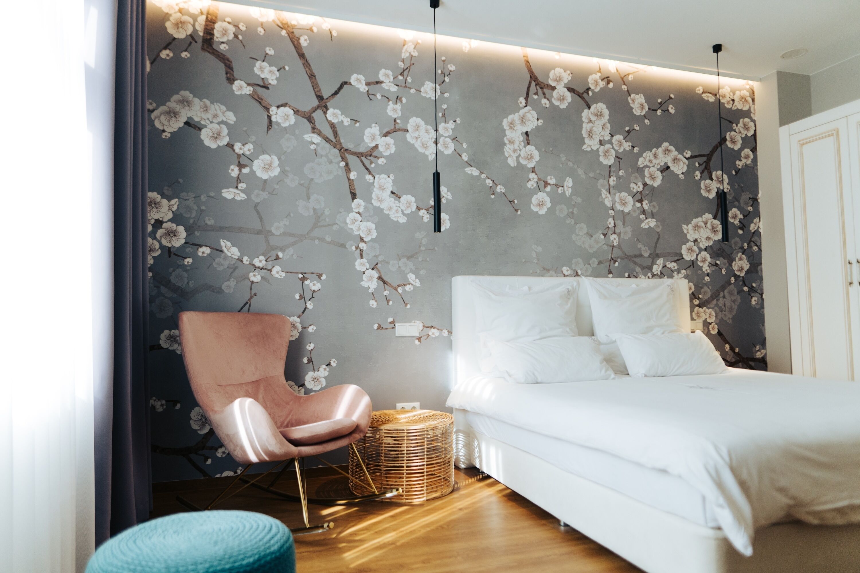 Un dormitorio con una cama, una silla y una pared con diseño floral.