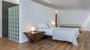 Un dormitorio con cama, mesitas de noche, un tocador de madera y una pared con detalles de vidrio con motivos.