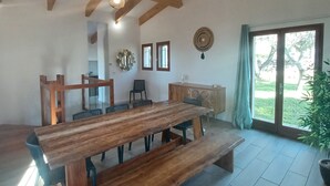 A spacious dining area with a wooden table and benches, a wooden ceiling with exposed beams, and a view of the outdoors through a large window. - SEASIDE VILLA PADULINA WITH SWIMMING POOL (Galéria)