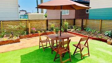 A patio with a table and chairs, surrounded by a wooden fence and a garden.