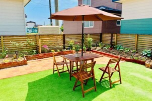 Eine Terrasse mit Tisch und Stühlen, umgeben von einem Holzzaun und einem Garten.