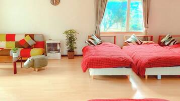 A room with two beds, a sofa, a small table, and a window with curtains.
