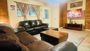 Un salon avec un canapé en cuir, une table basse et un téléviseur fixé au mur.
