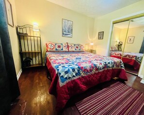 Een slaapkamer met een groot bed, een nachtkastje, een spiegel en een raam.