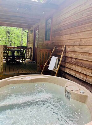 En træhytte med jacuzzi, spisebord og stole udenfor.