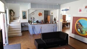 A hotel lobby with a reception desk, a staircase, a black sofa, and a painting on the wall.