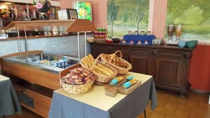 A buffet setup with various food items, including baskets of bread and pastries, and a refrigerator with beverages.