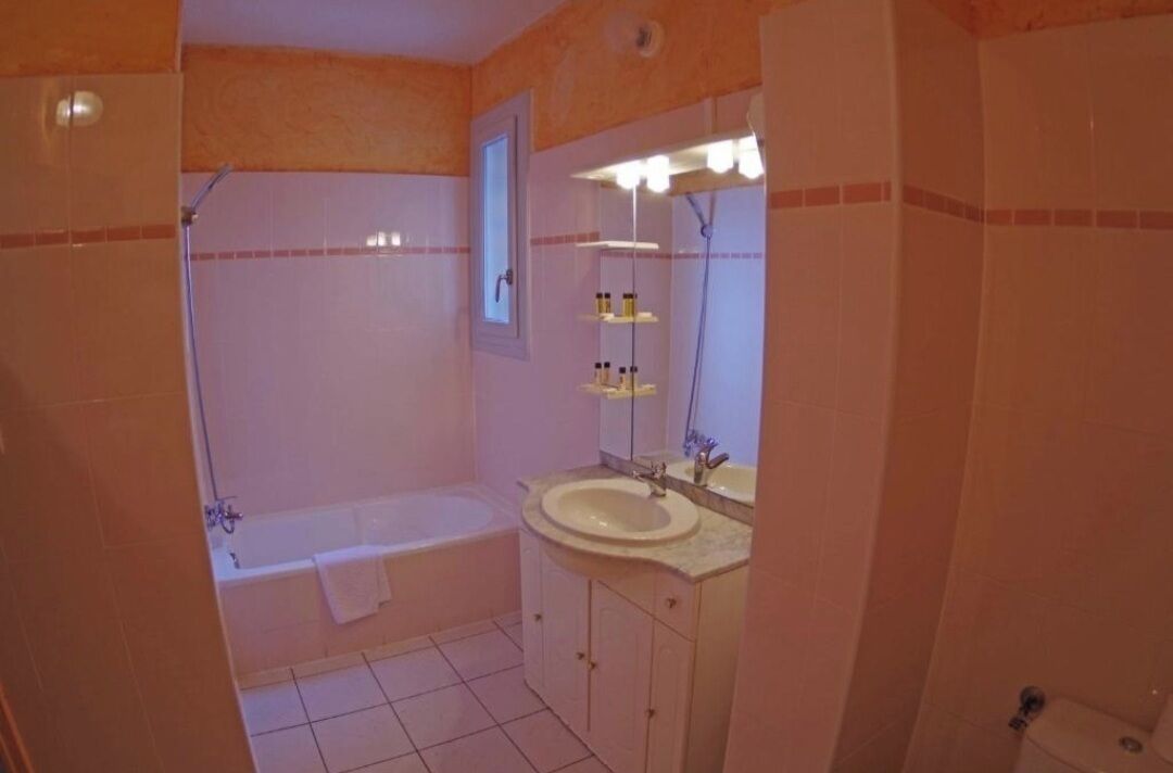 A bathroom with a bathtub, a sink, and a mirror.
