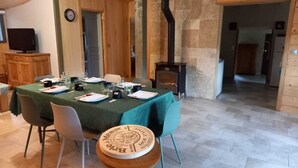 A dining area with a table set for four, a wooden bench, and a stone fireplace. - Cottage rental Gaillac countryside (Técou)