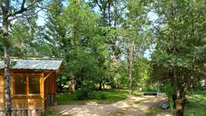 A rustic cabin with a gravel path leading to it, surrounded by dense trees. - Cottage rental Gaillac countryside (Técou)