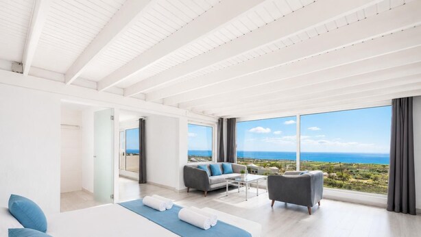 A modern hotel room with a large bed, a sofa, a coffee table, and a balcony with a view of the sea. - The View - Four Bedroom Villa, Sleeps 8 (Tías)