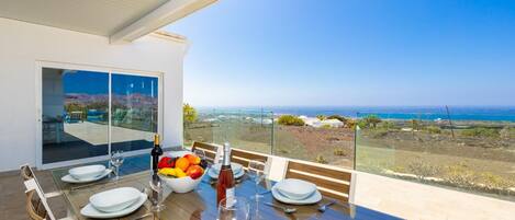 A dining area with a table set for four, overlooking a coastal landscape.