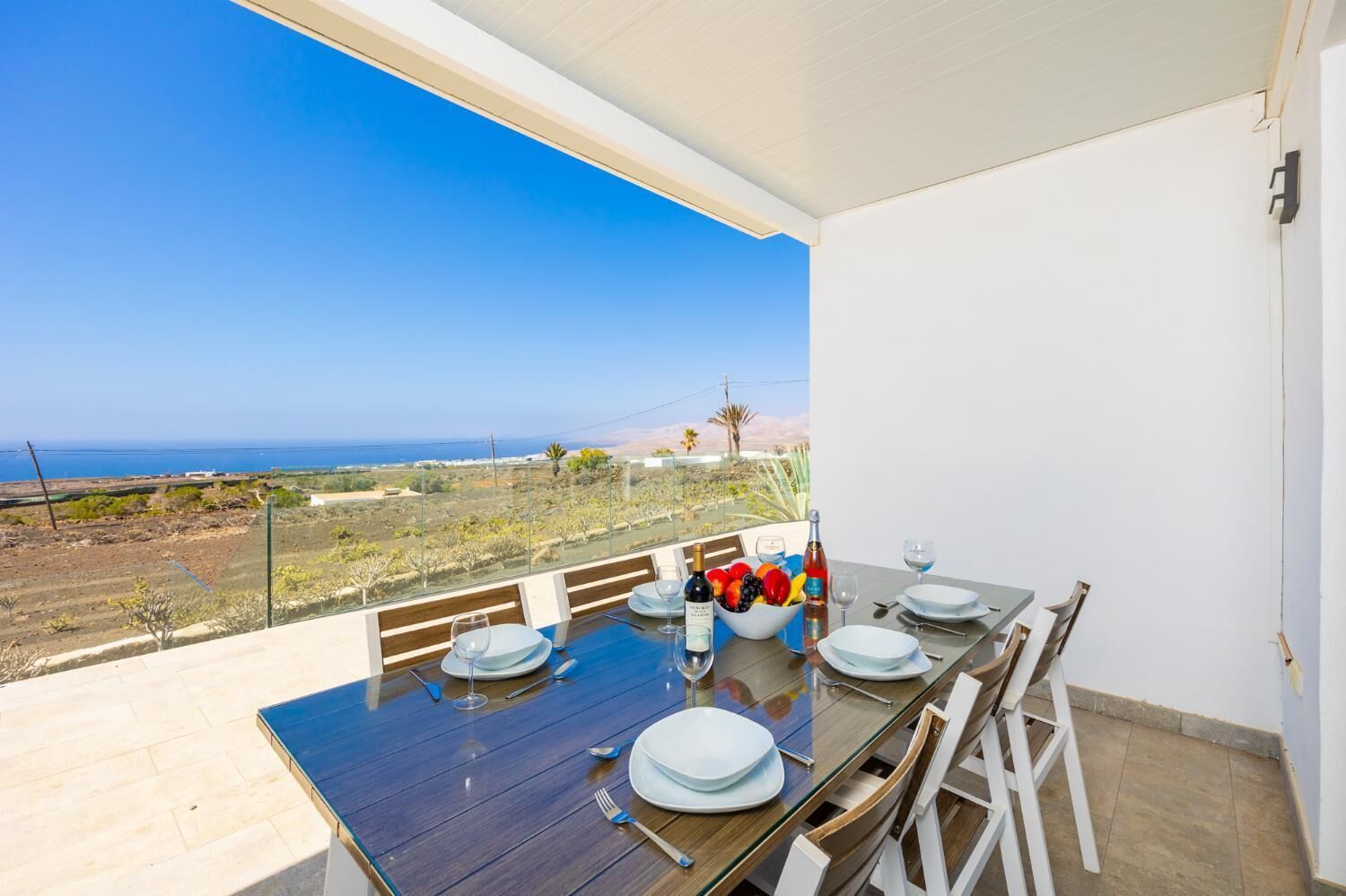 Un coin repas avec une table dressée pour quatre personnes, donnant sur un paysage côtier.
