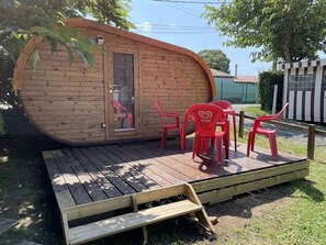 A wooden cabin with a deck and red plastic chairs.