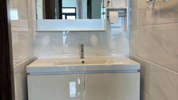 A bathroom with a white sink, mirror, and cabinet.