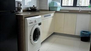 A compact kitchen with a built-in washer, a sink, and a window with a view of buildings. - Seaview 2B2R 6pax Condo Forest City C5-2404 (Gelang Patah)