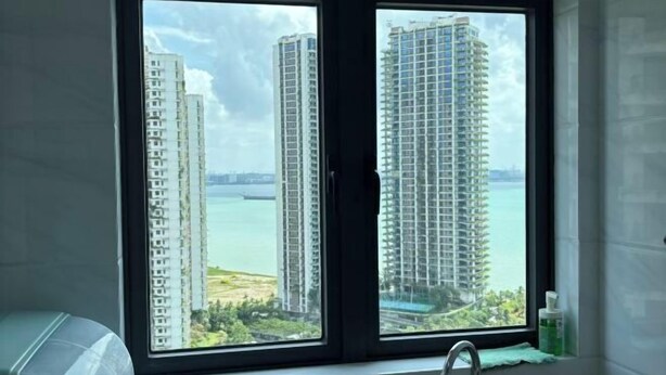 A bathroom with a window view of high-rise buildings and a body of water. - Seaview 2B2R 6pax Condo Forest City C5-2404 (Gelang Patah)