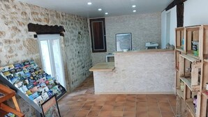 A reception area with a stone wall, tiled floor, wooden shelves, and a counter.