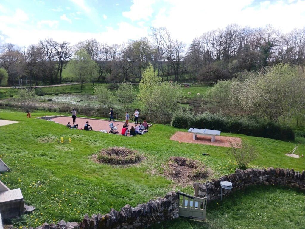 A park with a stone wall, a bench, and a pond.