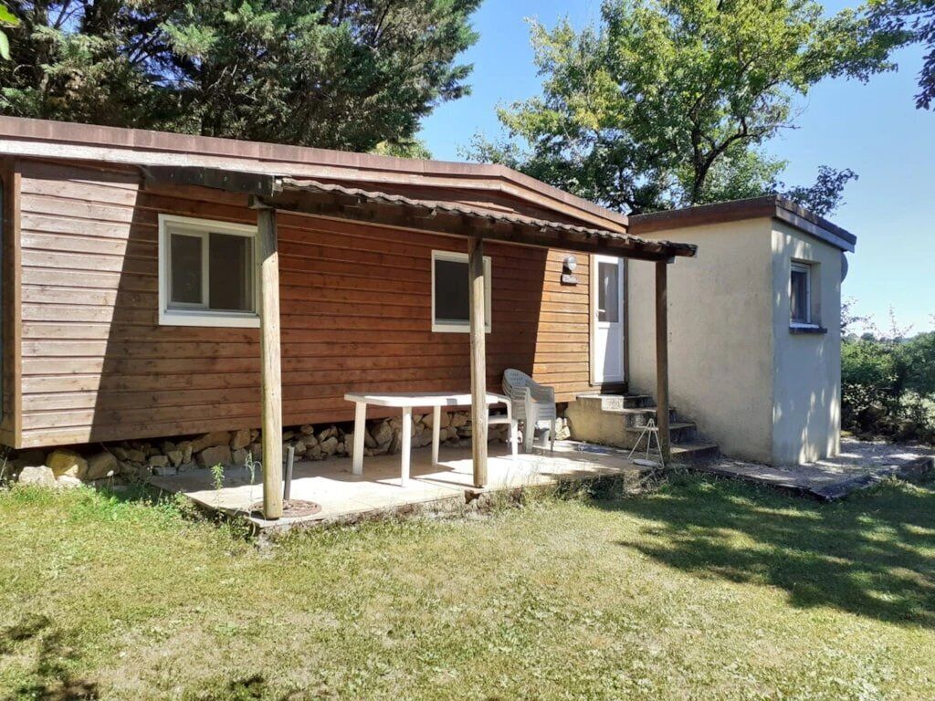 A wooden cabin with a porch, a small table, and a chair.